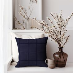 two vases with flowers and a pillow on a white bench in front of a mirror