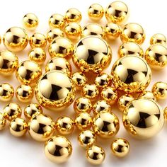 many shiny gold balls are scattered on a white surface, including one in the middle