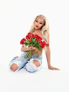 a woman sitting on the floor with flowers in her hands