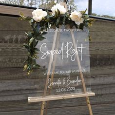 a welcome sign with flowers and greenery on it