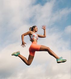 a woman jumping in the air while wearing orange shorts