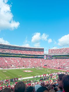 a large stadium filled with people watching a football game on a clear blue sky day