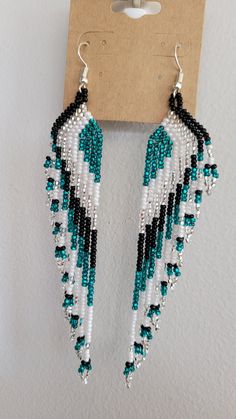 a pair of blue and white beaded earrings hanging from a hook on a wall