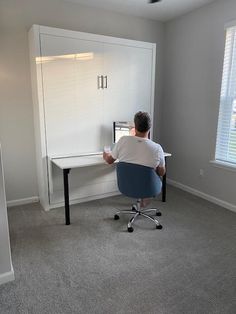 a man sitting at a desk in front of a computer monitor on top of a white cabinet