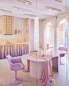 a dining room with purple chairs and a white table in front of a mirrored wall