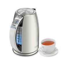 a silver coffee maker next to a cup of tea