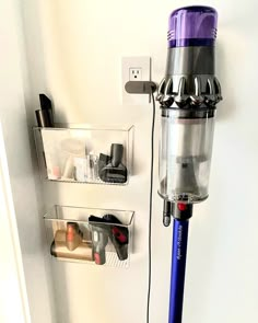 a purple and silver vacuum is hooked up to a wall with shelves on the side