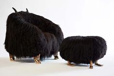 two black furry animals standing next to each other on a white surface with gold legs