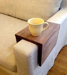 a coffee cup sitting on top of a wooden table next to a white couch in a living room