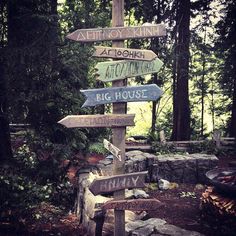 a wooden sign post with many different signs on it's side in the woods