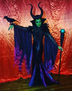 a woman dressed as maleficent in front of a red curtain