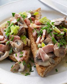 two pieces of bread with meat and vegetables on it sitting on a plate next to a fork