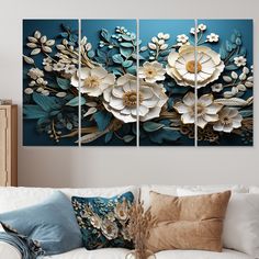 three panels of flowers on a blue wall in a living room with white couches and pillows