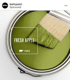 a green paint can with a brush in it and the words fresh apple painted on it