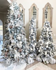 three decorated christmas trees sitting in front of mirrors