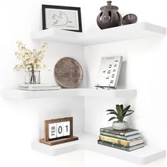 three white shelves with books, vases and pictures on top of each shelf in the corner