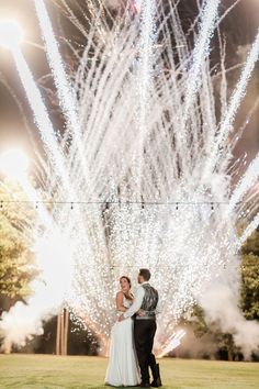 a bride and groom standing in front of fireworks