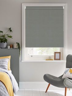 a bedroom with grey roller shades in the window and yellow accents on the bedding