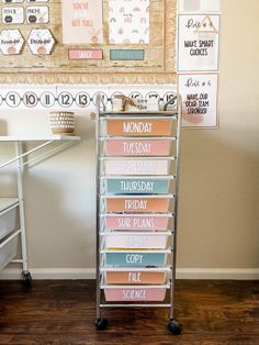 a metal cart with lots of cards on it in front of a wall mounted bulletin board