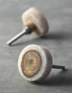 two wooden knobs sitting on top of a gray floor next to each other with nails sticking out of them