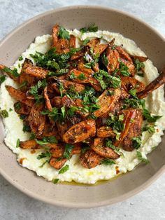 a bowl filled with mashed potatoes covered in parsley and garnished with meat