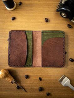 two leather wallets sitting on top of a wooden table next to coffee beans and scissors