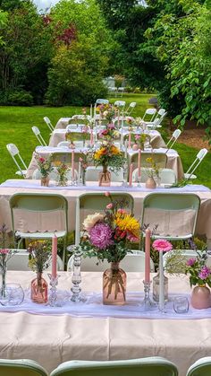 a long table is set up with flowers and vases on it for an outdoor wedding reception