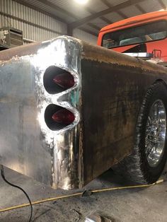 an old truck is being worked on in a garage with no wheels or tires, and the rear lights are visible