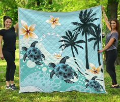 two women holding up a quilt with turtles on it