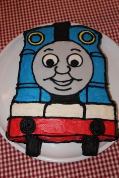 a thomas the train birthday cake on a plate with red and white checkered tablecloth