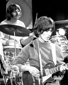 the rolling stones performing on stage with their guitars in front of drums and drumsticks