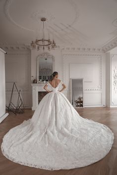 a woman in a white wedding dress is standing on the floor with her back to the camera