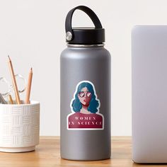 a woman with glasses sticker on a water bottle next to a laptop and pencils