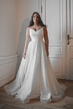 a woman in a white wedding dress posing for the camera with her hands on her hips