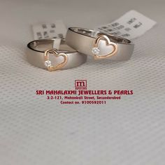 two silver rings with hearts on them sitting next to each other in front of a price tag