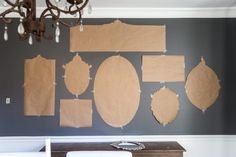 several pieces of brown paper taped to the wall next to a table with chairs and a chandelier