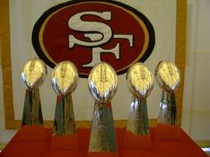 five football trophies sitting on top of a red table