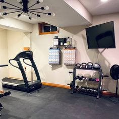 an exercise room with treadmills, television and other personal items on the wall