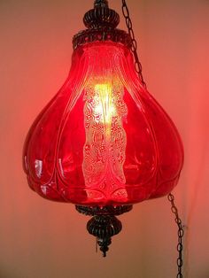 a red glass light hanging from a chain