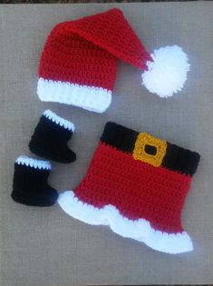 two crocheted santa hats and mittens are laying on the ground next to each other