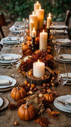 a table set with candles, plates and pumpkins