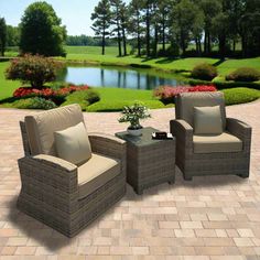 three wicker chairs and a table on a brick patio with water in the background