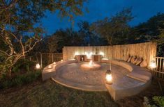 an outdoor seating area with candles lit up in the middle and lights on the side