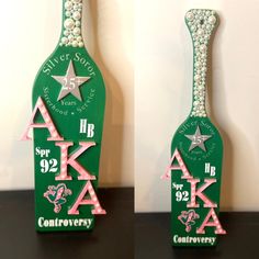 two green bottles decorated with pearls and letters