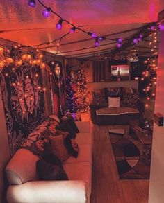 a living room filled with lots of furniture and christmas lights hanging from the ceiling above