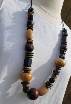 A variety of wooden beads styled together on a leather cord creating a bold and unique statement piece.  Necklace is approximately 32 inches long.  Every purchase is packaged for gift giving. Everyday Brown Wooden Beaded Necklaces, Brown Long Beaded Necklace With Wooden Beads, Long Brown Beaded Necklace With Wooden Beads, Adjustable Brown Long Necklace With Large Beads, Brown Wooden Beads Long Necklace, Artisan Necklace With Brown And Black Beads, African Jewelry, Chain Styles, Wooden Beads