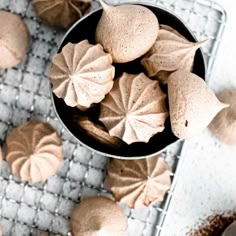 some cookies are sitting in a bowl on a cooling rack next to other pastries