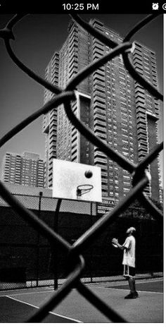 a man standing on top of a tennis court holding a racquet next to a basketball hoop