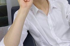 a person sitting down with a cell phone in their hand and wearing a white shirt