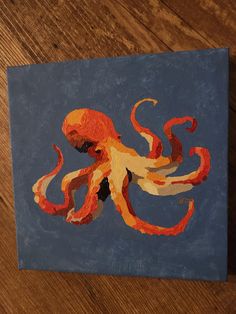 an orange and black octopus painted on a blue canvas with wood flooring in the background